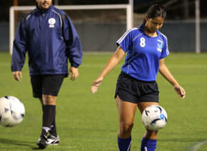 Guam U16 Women's national team head coach Brett Maluwelmeng (in background) watches as Maria Abbey Iriarte participates in a warm up drill during a recent open team tryout session for the team at the Guam Football Association National Training Center.