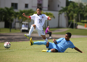 Hong Kong's Lam Tsz Fung leaps to avoid a slide tackle by Northern Mariana Islands' Kirt Andon in a Day 2 match of the EAFF East Asian U13 2015 Festival held at LeoPalace Resort Guam Monday.
